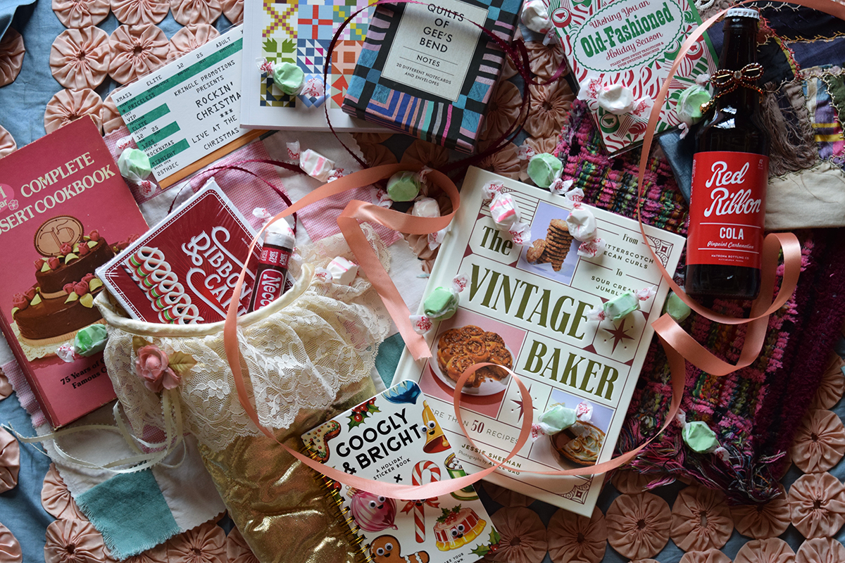 Collection of vintage-themed cookbooks and a bottle of Red Ribbon Cola on a decorative surface.